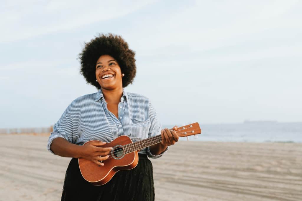 girl playing ukulele beach